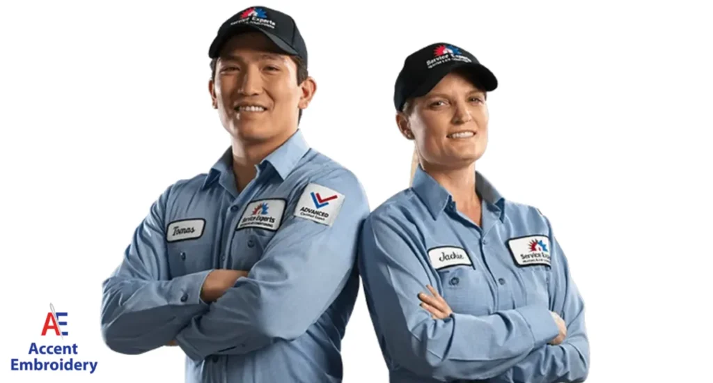 Two men wearing blue shirts and caps stand side by side, representing a local embroidery shop's team spirit.